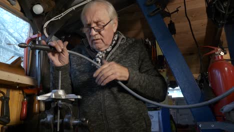 senior metal worker uses small honing tool in a dark workshop