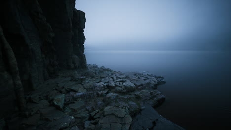 misty shoreline with rocky landscape under overcast sky at dawn