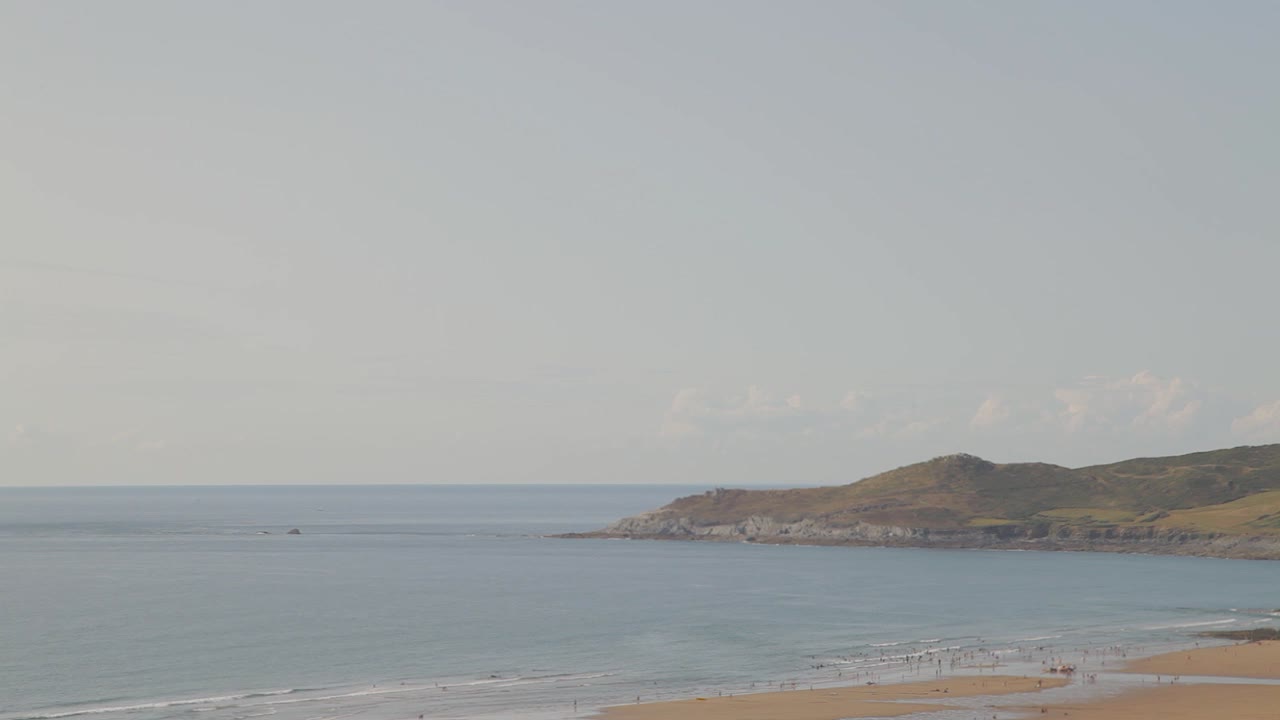 playa de la bahía de woolacombe con baggy point y gente nadando en los calurosos días de verano