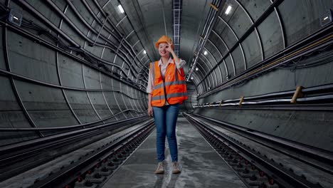 full body of asian female engineer with safety helmet showing ok hand sign over eye and smiling to camera in underground subway tunnel
