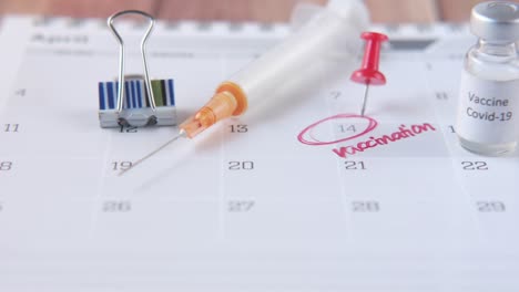 ampolla de vidrio con vacuna y jeringa en el calendario
