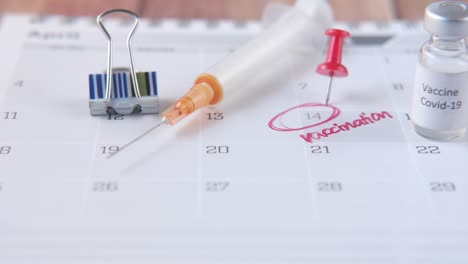 vaccine day concept glass ampoule with vaccine and syringe on calendar