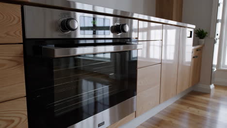 modern kitchen with stainless steel oven and light wood cabinets