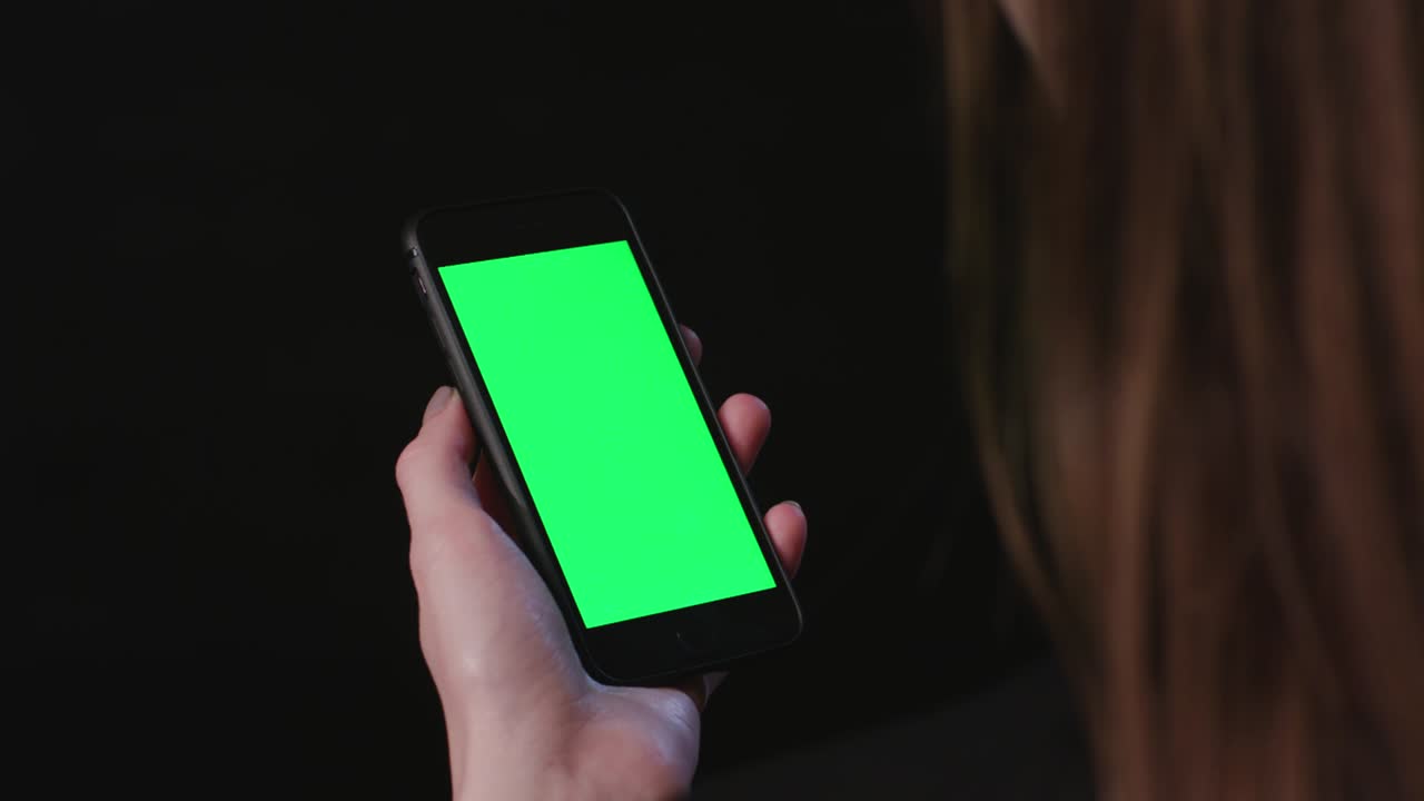 여성이 초록색 화면으로 전화를 들고 있습니다.