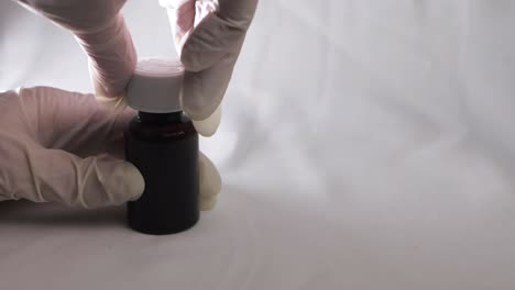 putting cap on bottle of medicine with white gloves close up shot