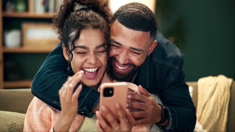 a happy couple laughing at a mobile phone