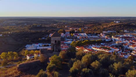 Drone-shot-of-a-tower-on-a-hill-by-a-village-in-Alentejo,-Portugal