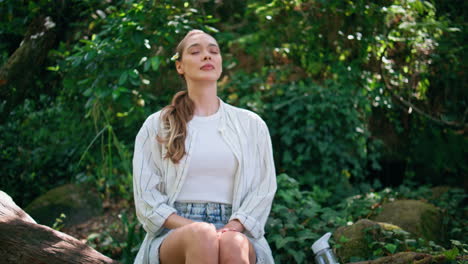 girl closing eyes forest breathing fresh air. calm woman sitting in green park