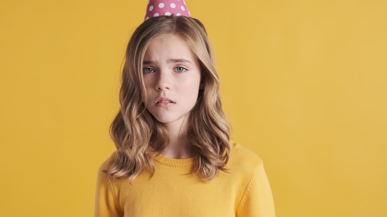 Sad teenage Caucasian girl wearing a party hat.