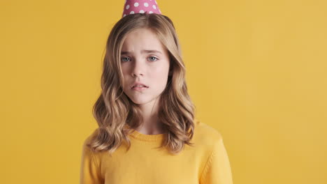 sad teenage caucasian girl wearing a party hat.