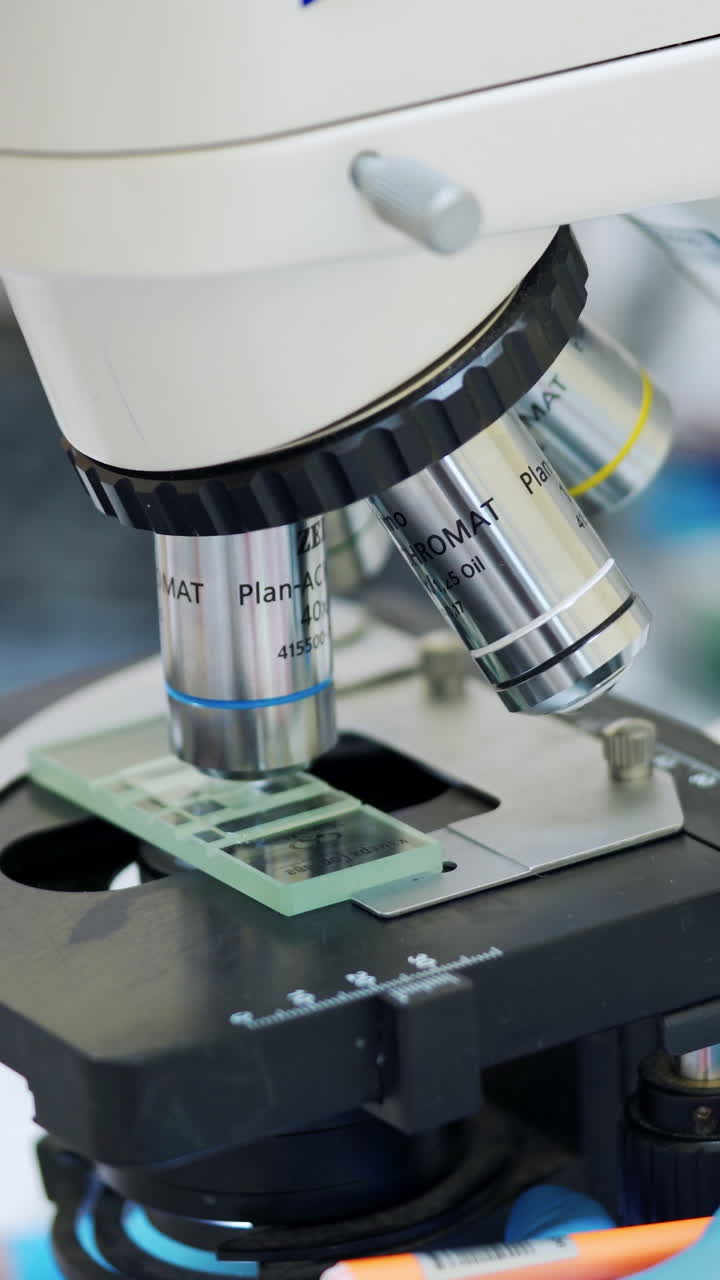 Medical equipment for blood examination. Scientist examining sample, looking into microscope. Vertical video