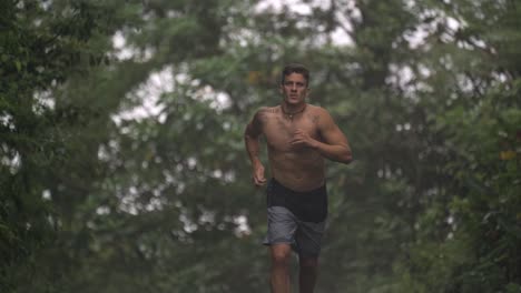 a shirtless man is captured mid-stride, running on a path surrounded by dense, green foliage