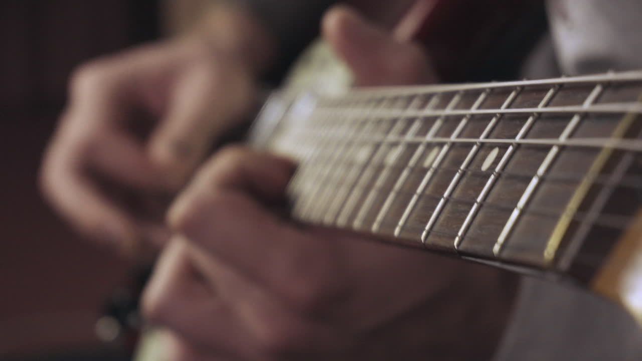 manos con un esmalte de uñas negro en mal estado tocando la guitarra