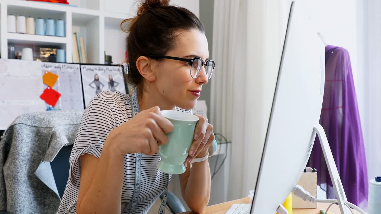 Designer donna che prende un caffè mentre lavora al computer 4k