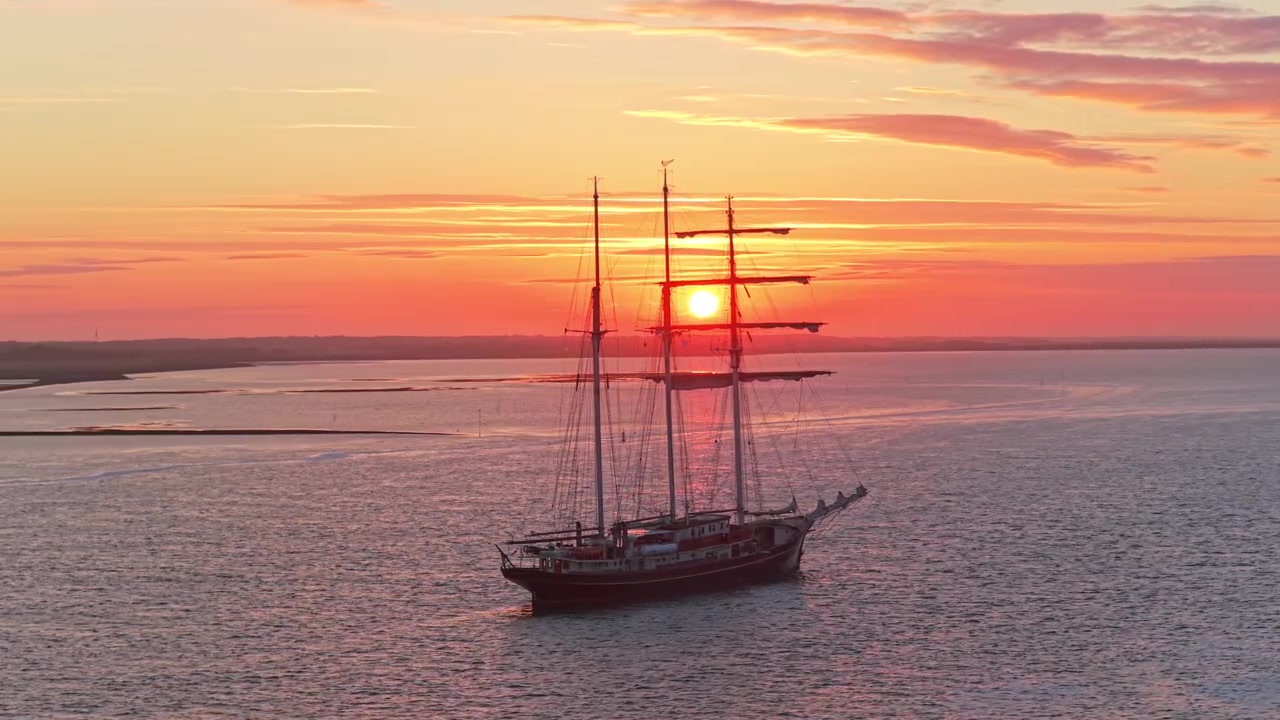 Terschelling'de gün batımında Wadden Denizi'nde seyreden Gulden Leeuw yelkenli gemisi