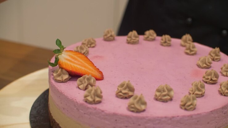 Woman decorating cream cake with strawberries on spinning plate