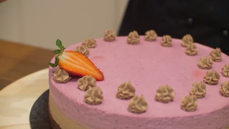 Woman-decorating-cream-cake-with-strawberries-on-spinning-plate