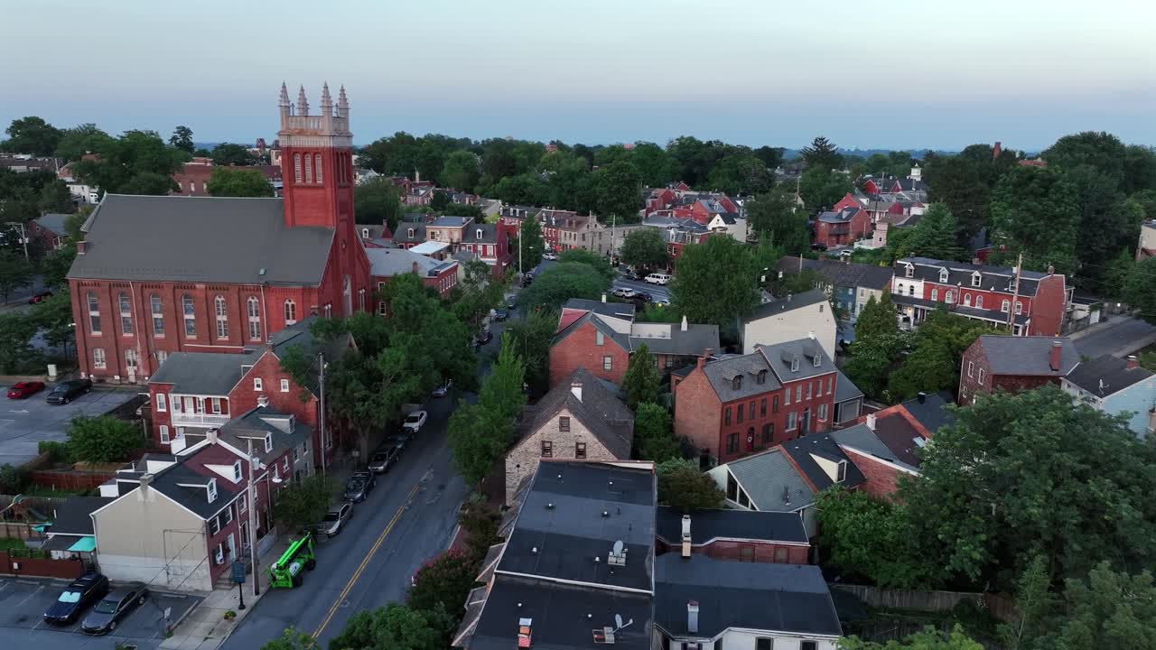 Aerial flyover historic town with ancient buildings and old church in Lancaster, Pennsylvania. Dusk scene in summer season. Brick houses on small cozy town