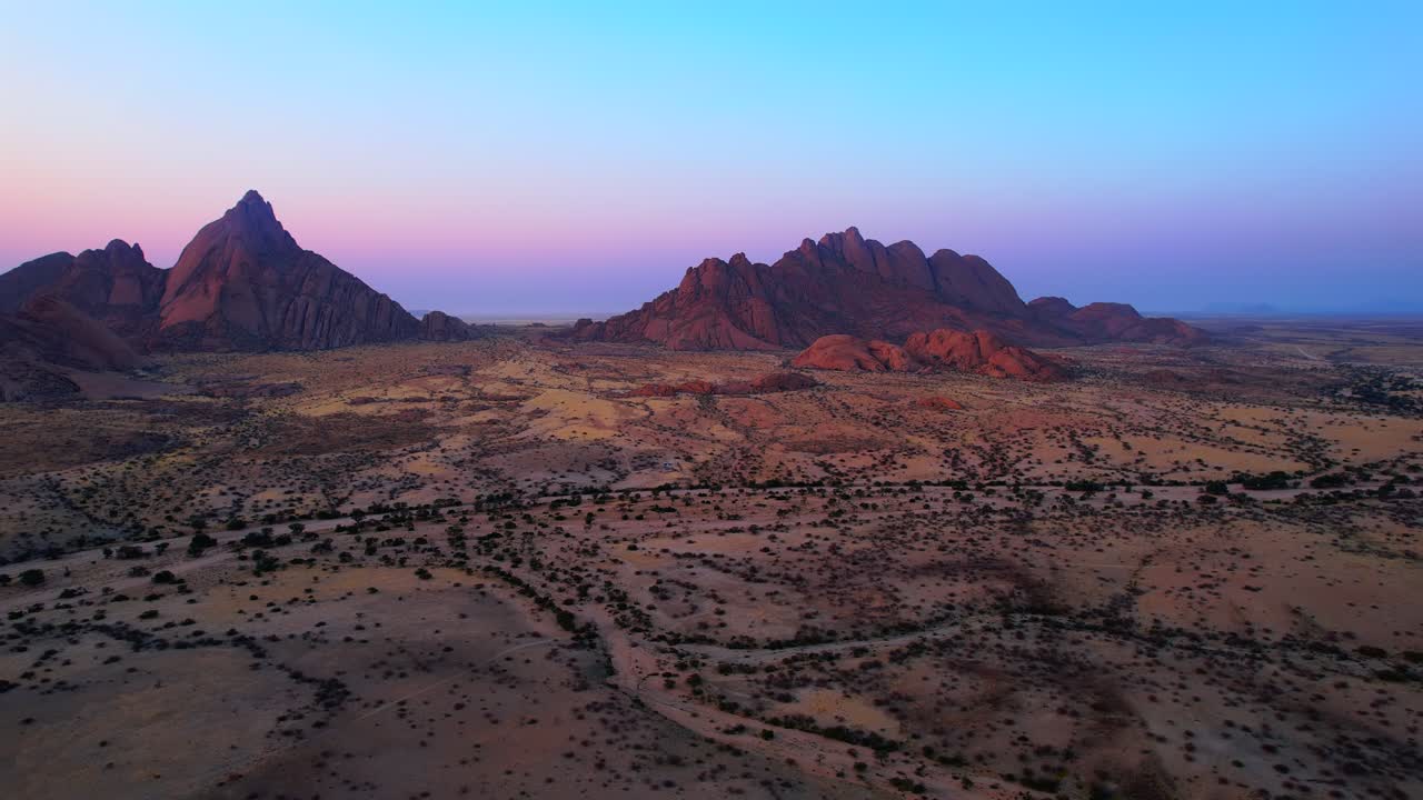 Pink and purple dusky sunset over Spitzkoppe granite inselbergs, Namib Desert. Smooth aerial