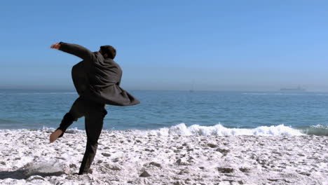 businessman jumping then revolving on the beach