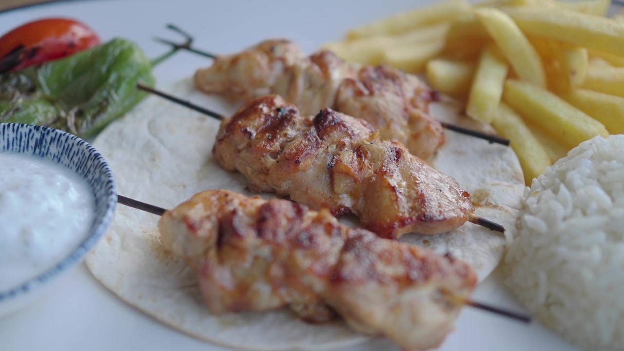 Grillet kyllingspyd servert med ris og pommes frites.