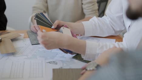 close-up view of design professionals examining and choosing from a variety of color swatches over architectural plans during a project meeting