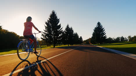 Mujer-Joven,-Andar-En-Bicicleta-En-La-Atardecer-Vista-Trasera-Lenta-Video