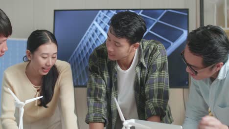 primer plano de un hombre y una mujer asiáticos en un grupo de ingeniería discutiendo durante una reunión sobre un modelo de casa pequeña con panel solar en la oficina