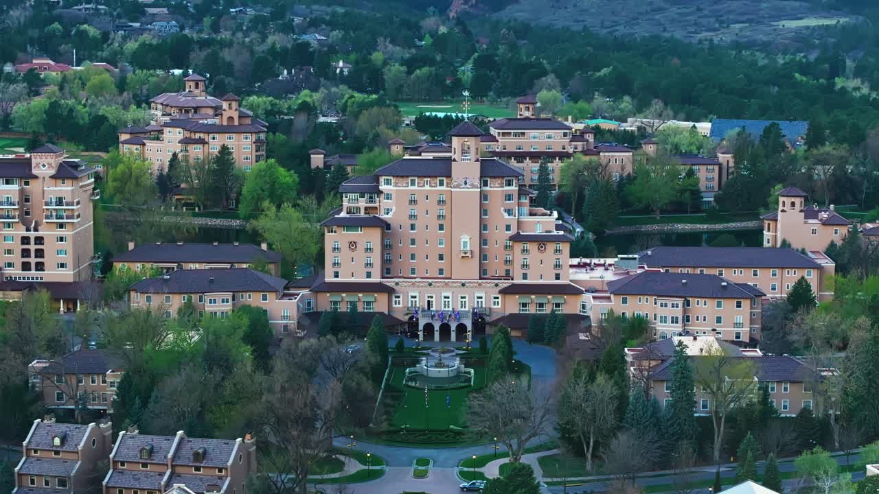 Aerial pan of Broadmoor entrance surrounded by lush greenery and scenic mountain backdrop