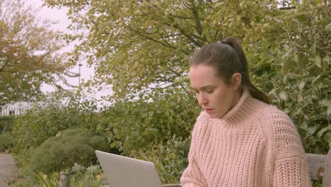 female working on a laptop in a park stressed