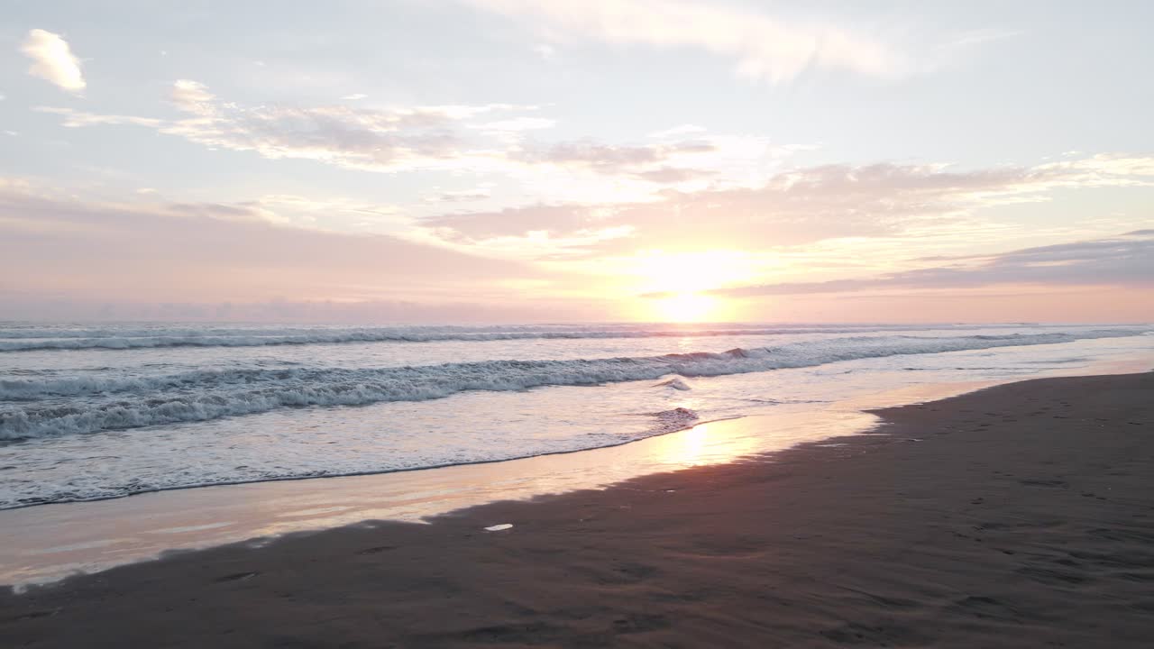 Drone flight over the sandy beach of playa bandera at sunset towards the surf of the ocean in costa rica