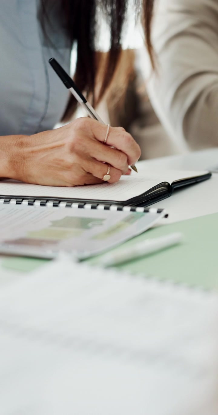 Donna professionista che scrive appunti su un taccuino durante una riunione di lavoro