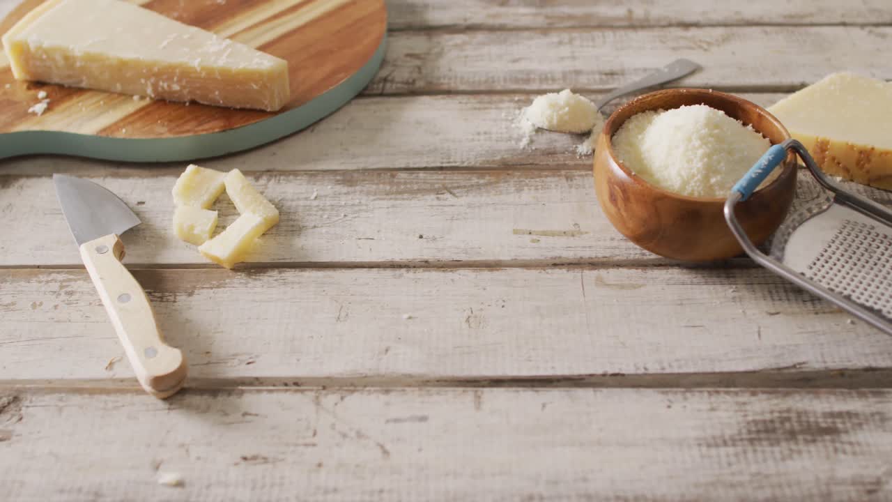 video de queso parmesano y parmesano rallado en un tazón con rallador en una mesa rústica con espacio para copiar
