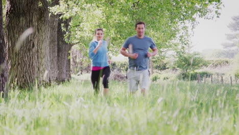 crane shot of couple exercising running through countryside field