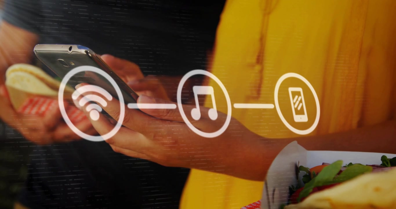 Coppia che tocca lo schermo dello smartphone a una bancarella di cibo, attivando una sovrapposizione di catena tecnologica di streaming musicale.