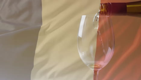 composite of white wine being poured into glass over flag of france background