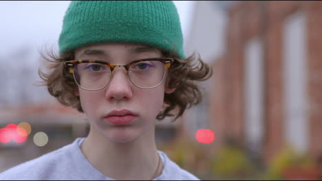 Portrait-of-teen-boy-with-glasses-and-green-hat-outside