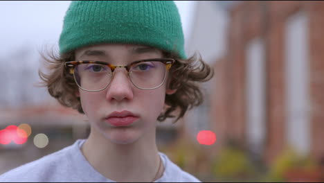 portrait of teen boy with glasses and green hat outside