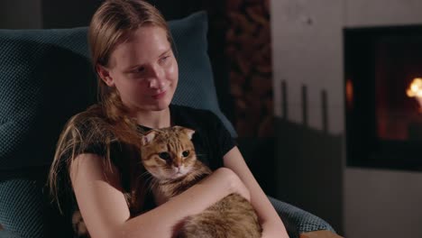 teenage girl with a scottish fold cat by the fireplace