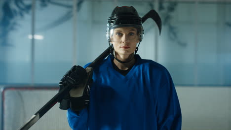 portrait of a happy female hockey player looking cheerfully at the camera on the ice arena