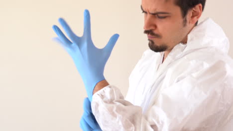médico con traje de ppe poniéndose guantes de látex azules