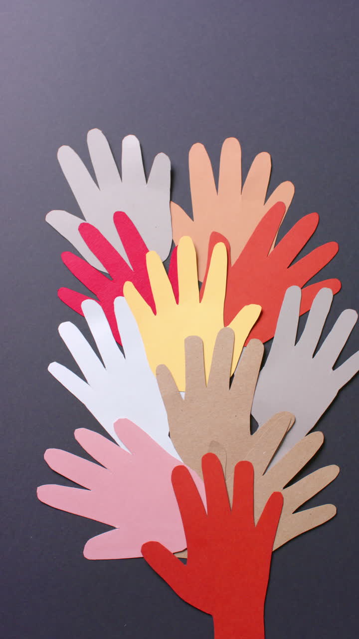 Vertical video of hands together made of colourful paper on gray background with copy space