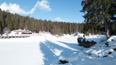 Aerial-Flying-Low-Over-Frozen-Frozen-Caumasee-Lake-Island-With-Trees