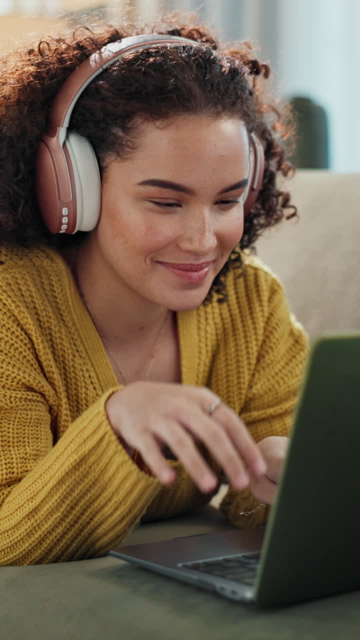 Jovem mulher com fones de ouvido trabalhando e sorrindo no laptop