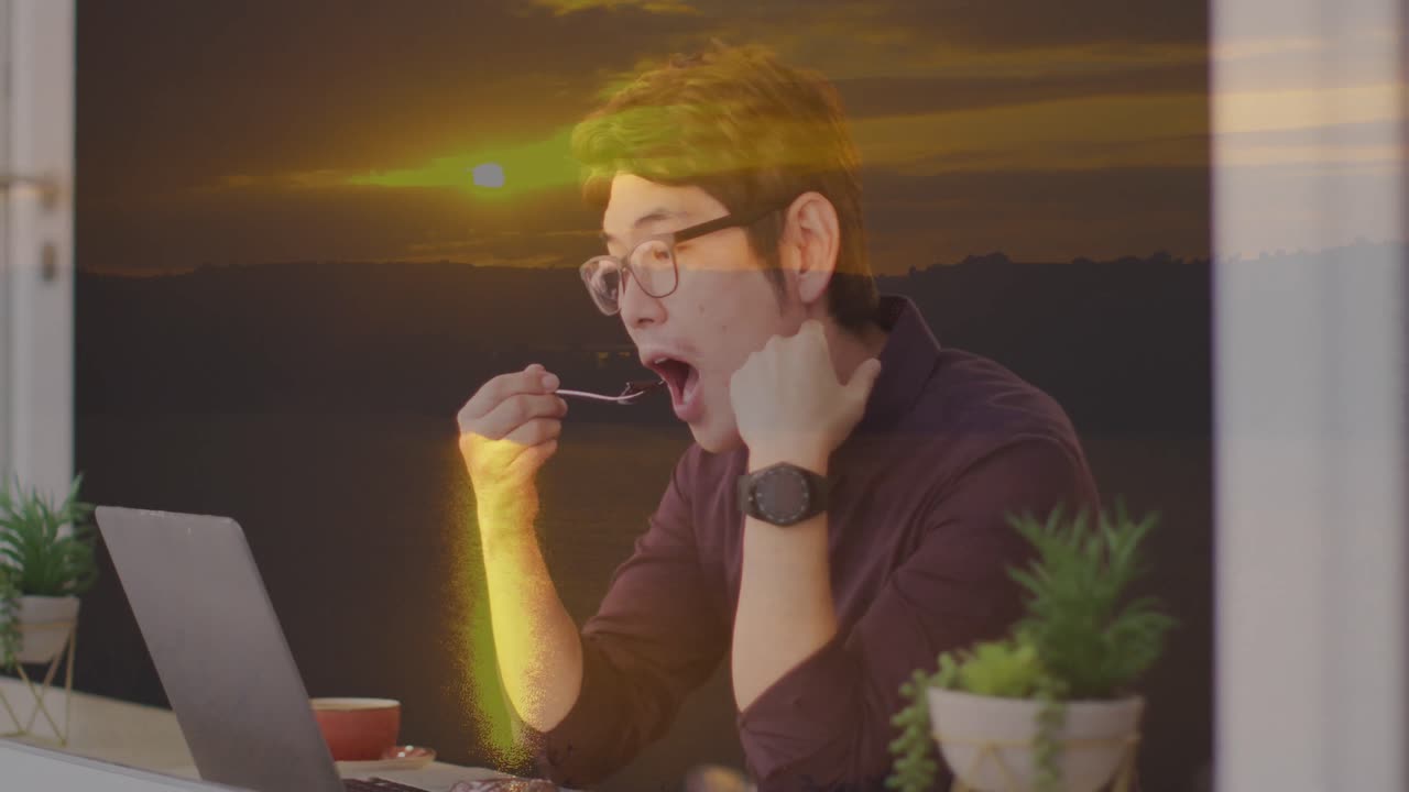 vista de la puesta de sol sobre un hombre de negocios asiático usando una computadora portátil en la oficina