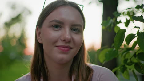 primer plano de una mujer con una cálida sonrisa, rodeada de árboles verdes y una suave iluminación exterior, creando una atmósfera serena en un entorno natural, perfecto para el estilo de vida