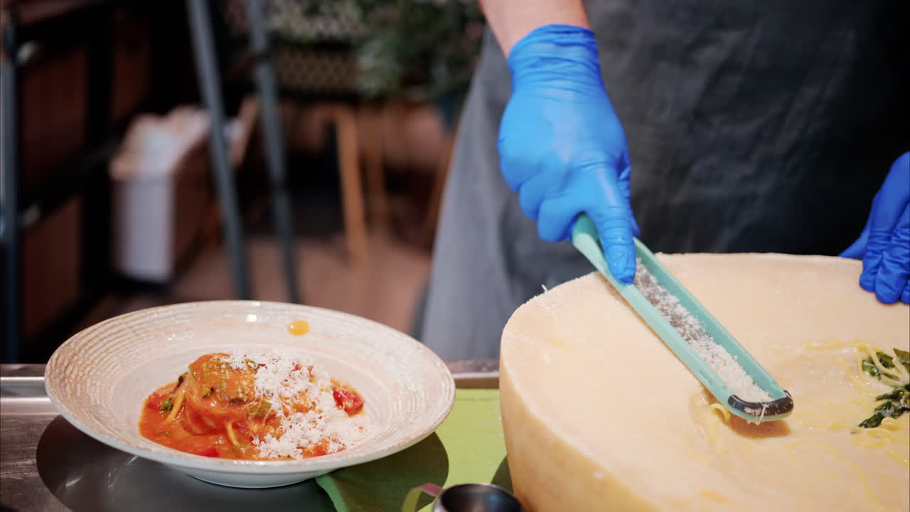 Man putting grated parmesan on pasta in a restaurant