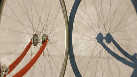 high angle view of bicycle wheel on the concrete road. seamlessly looping video with slowly spinning road bike wheel casting shadow over grey road surface. sport, commute, transportation concept. 4k