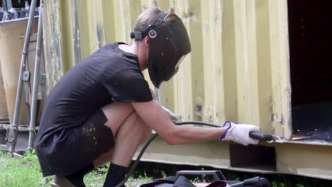 person welding a metal container with sparks flying