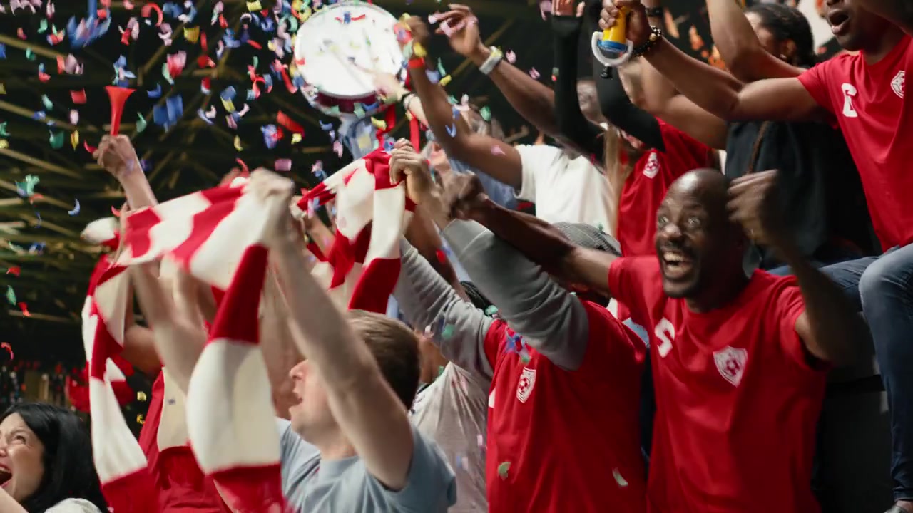 Aficionados eufóricos de fútbol lanzan confeti celebrando una gran victoria tras un gol de último minuto